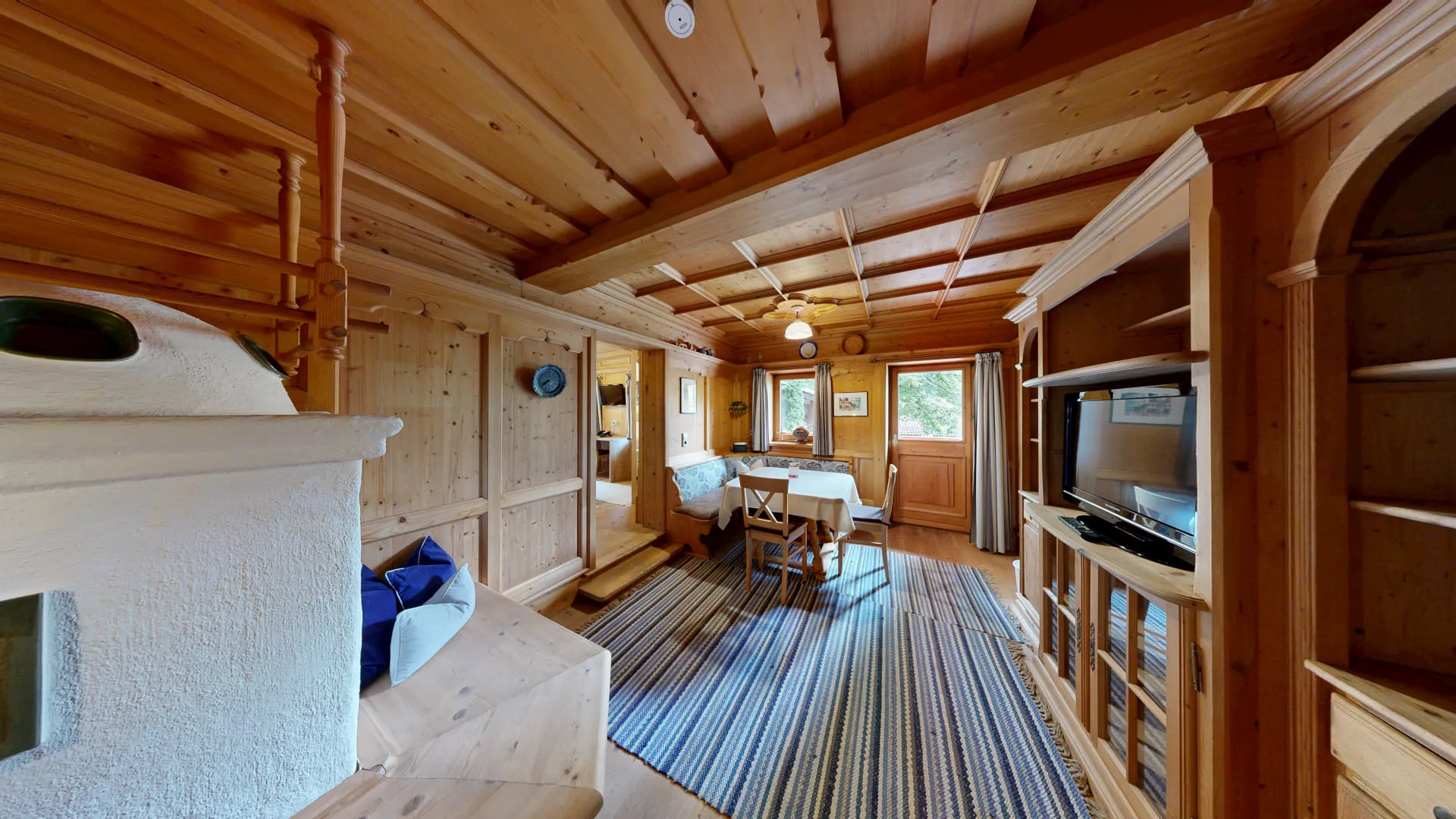 Holzverkleideter Wohnraum mit Tisch, Stühlen und Blick auf das Fenster.