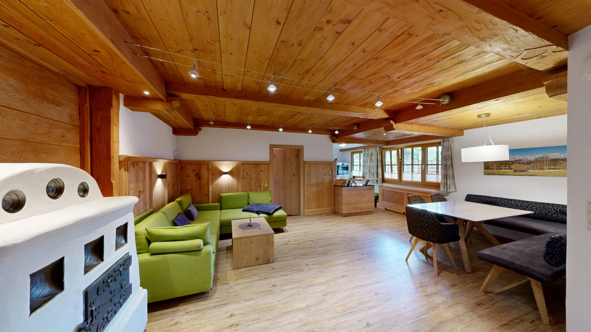 Helles, modernes Wohnzimmer mit Holzdecken, Couch und Esstisch.